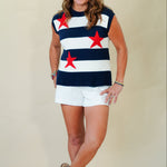 Woman wearing a sleeveless top with red star patterns and white shorts against a plain background