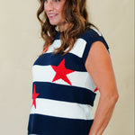 Woman wearing a sleeveless top with red star designs and white shorts on a beige background