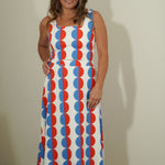 Woman wearing a sleeveless dress with red, white, and blue pattern against a plain background