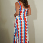 Woman wearing a sleeveless dress with red, white, and blue pattern against a plain background