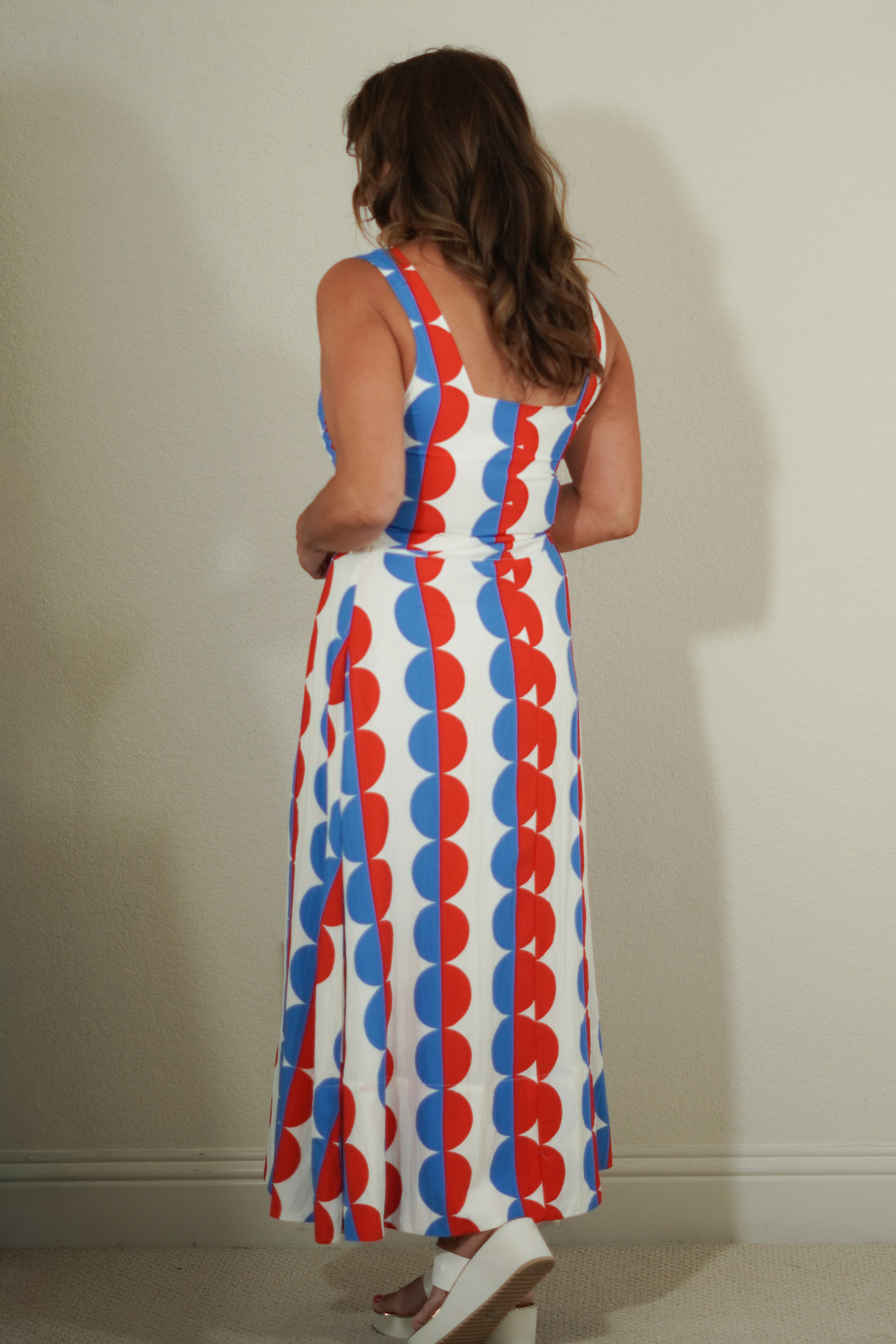 Woman wearing a sleeveless dress with red, white, and blue pattern against a plain background