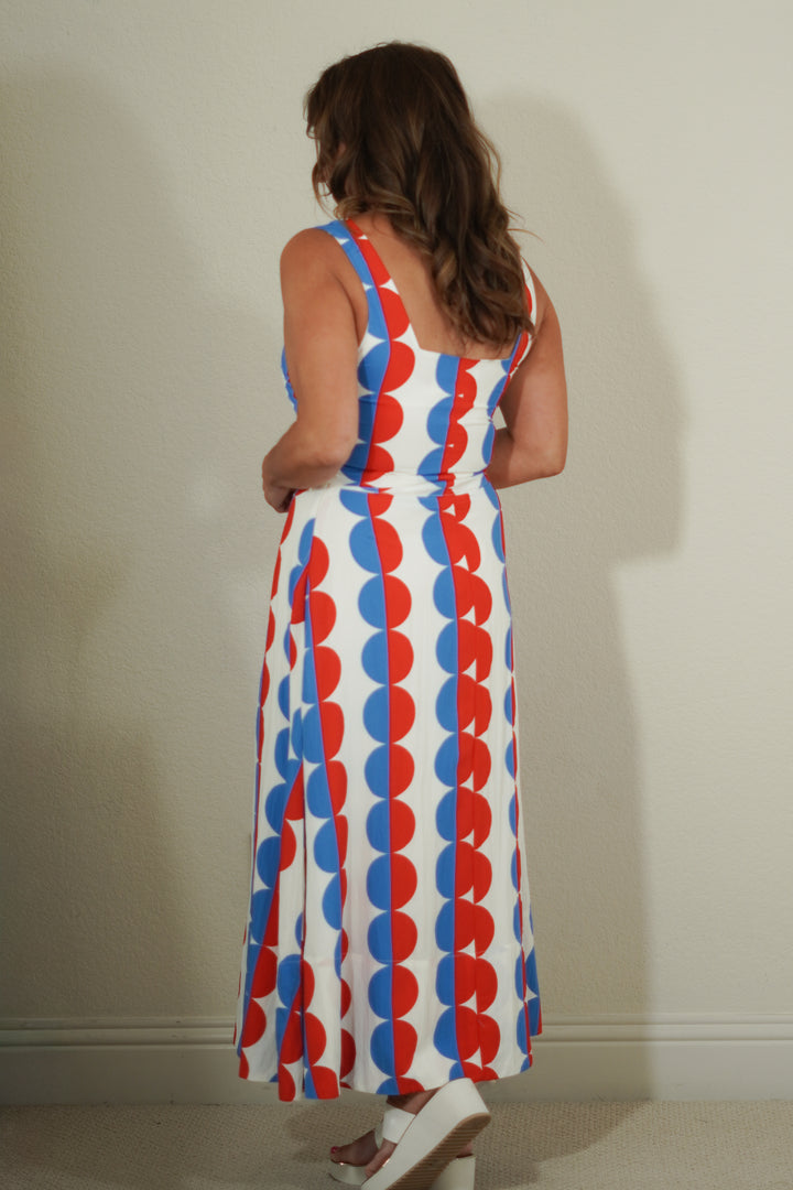 Woman wearing a sleeveless dress with red, white, and blue pattern against a plain background