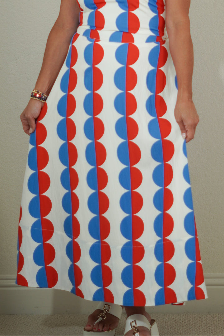 Woman wearing a sleeveless dress with red and blue circular pattern against a plain background