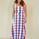 Woman wearing a sleeveless dress with red, white, and blue geometric pattern on a plain background