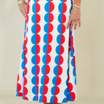 Woman wearing a sleeveless dress with red, white, and blue pattern against a plain background