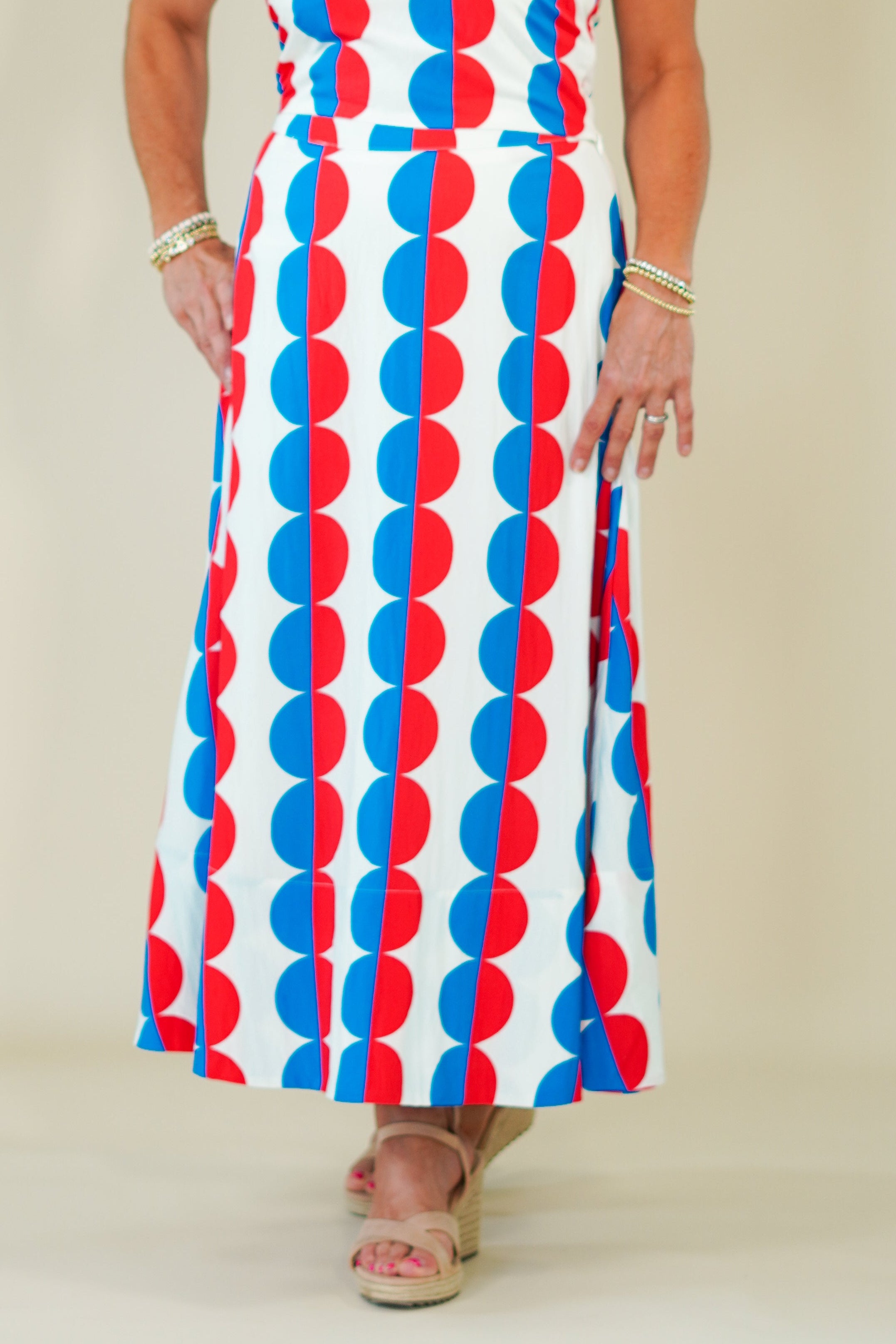 Woman wearing a sleeveless dress with red, white, and blue pattern against a plain background