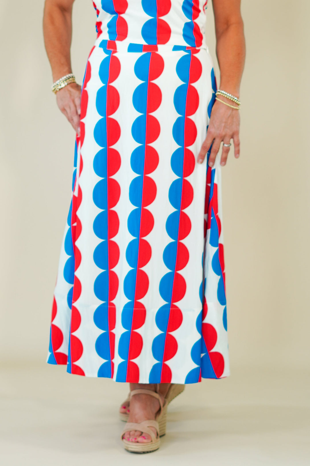 Woman wearing a sleeveless dress with red, white, and blue pattern against a plain background