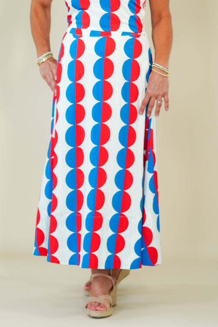 Woman wearing a sleeveless dress with red, white, and blue pattern against a plain background