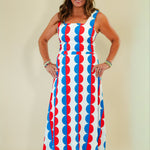 Woman wearing a colorful dress with geometric pattern on a plain background