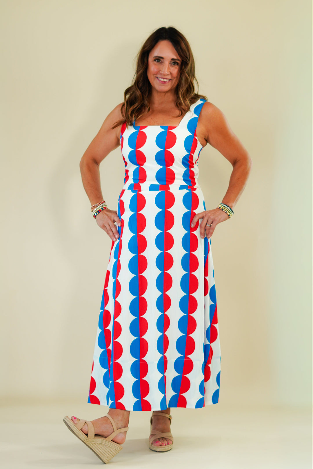 Woman wearing a colorful dress with geometric pattern on a plain background