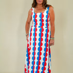 Woman wearing a sleeveless dress with red and blue circular pattern on a plain background