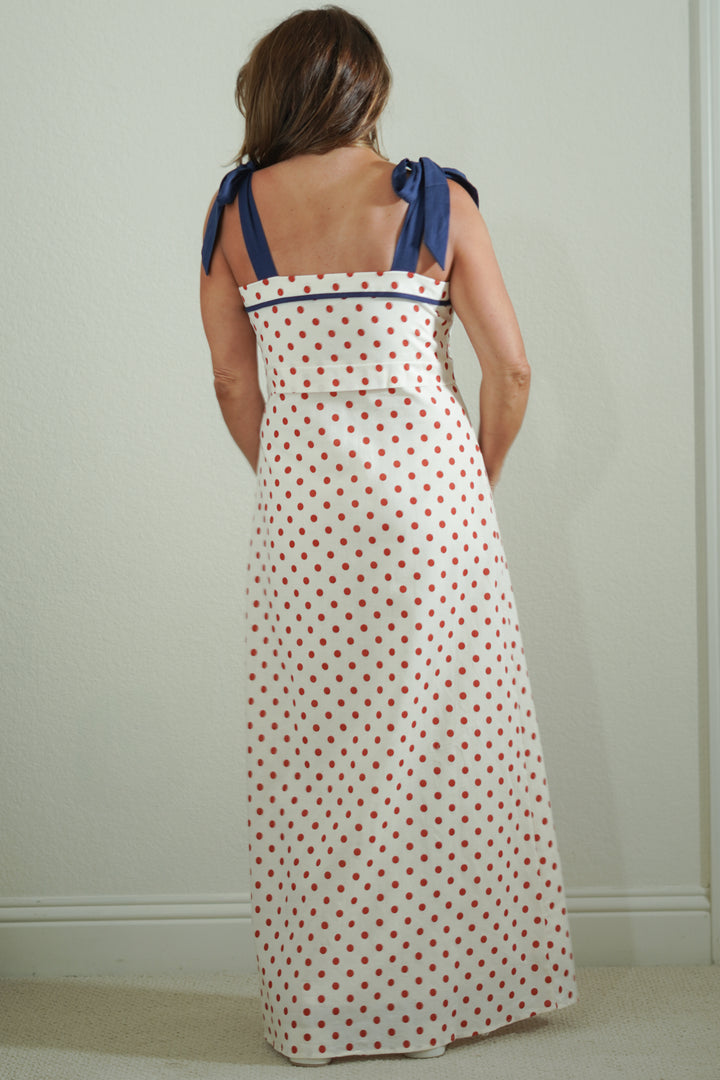 Woman wearing a polka dot dress with blue straps against a plain background