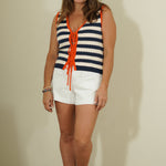 Woman wearing a striped sleeveless top and white shorts against a plain background