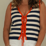 Woman wearing a striped sleeveless top with orange accents against a plain background