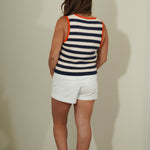 Person wearing a striped sleeveless top and white shorts against a plain wall.