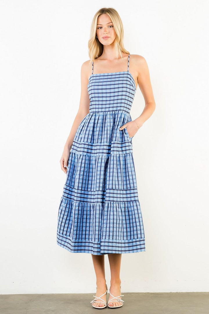 Woman wearing a blue checkered dress against a white background