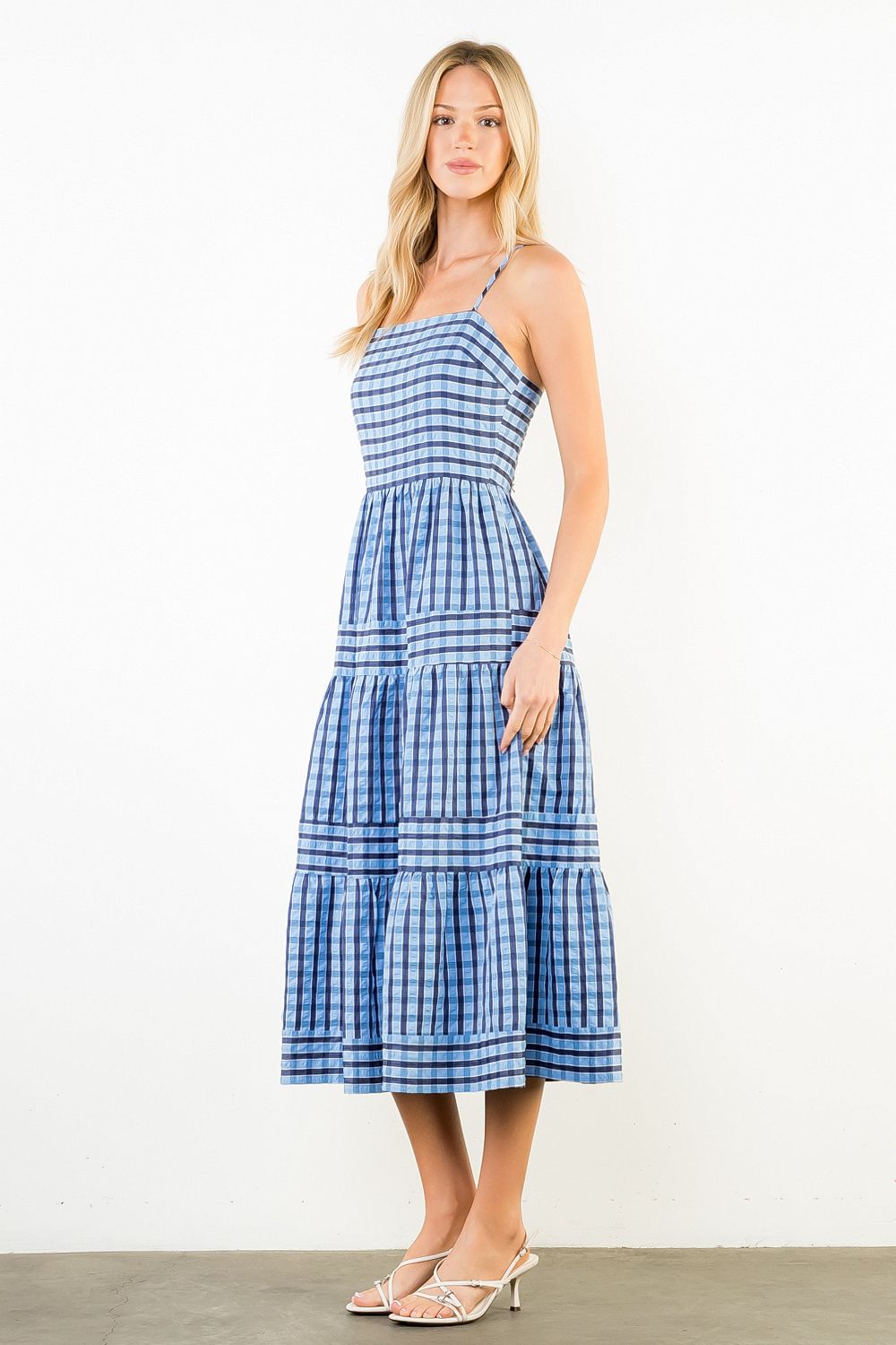 Woman wearing a blue and white checkered dress on a white background