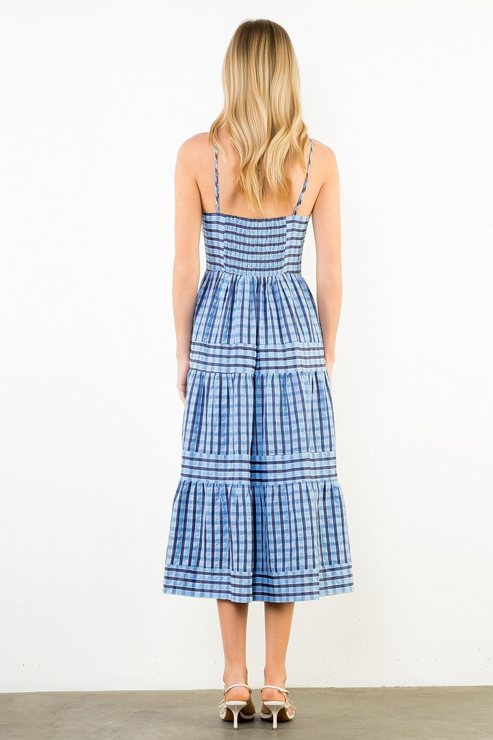 Woman wearing a blue and white checkered dress on a plain background