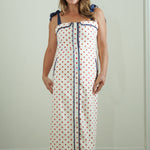 Woman wearing a polka dot dress with blue trim against a plain background
