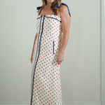 Woman wearing a long polka dot dress with blue accents against a plain background