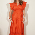 Woman wearing an orange dress standing in front of a mirror.