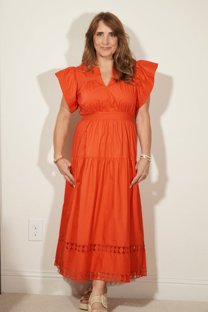 Woman wearing an orange dress standing in front of a mirror.