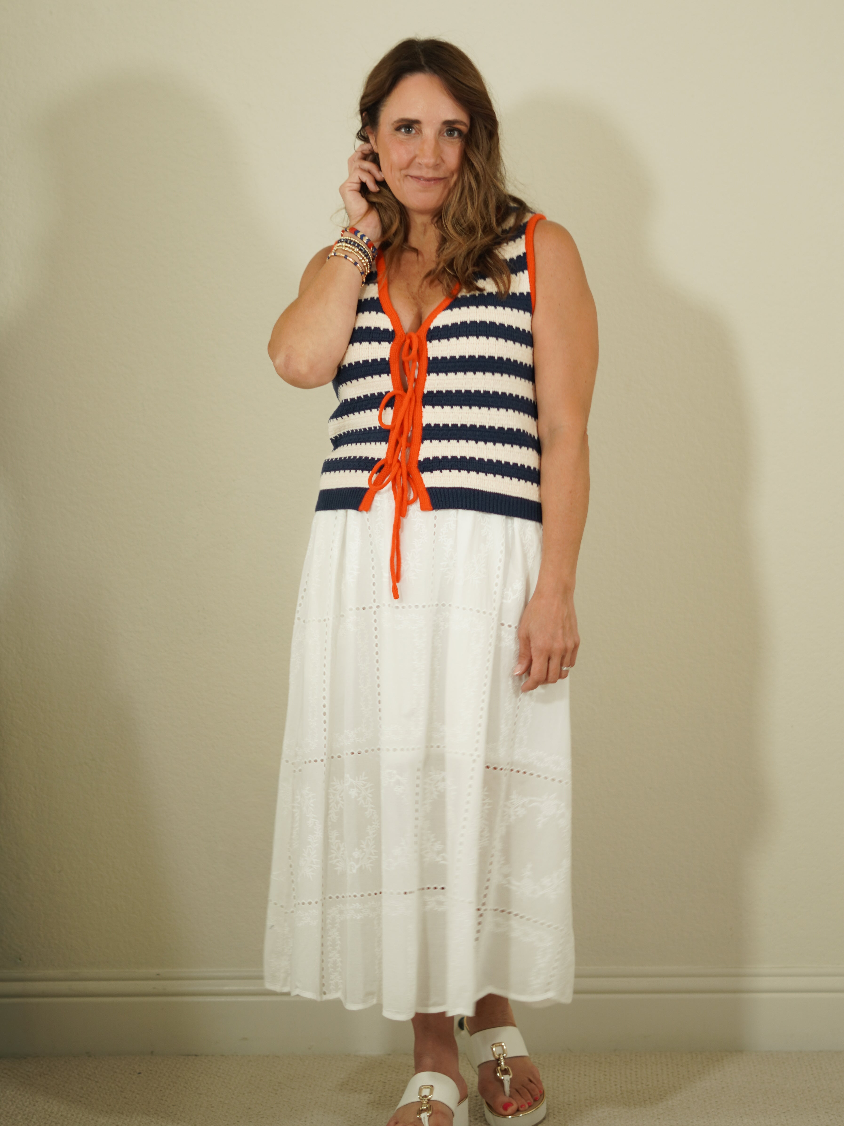 Woman wearing a striped dress with orange accents against a plain background