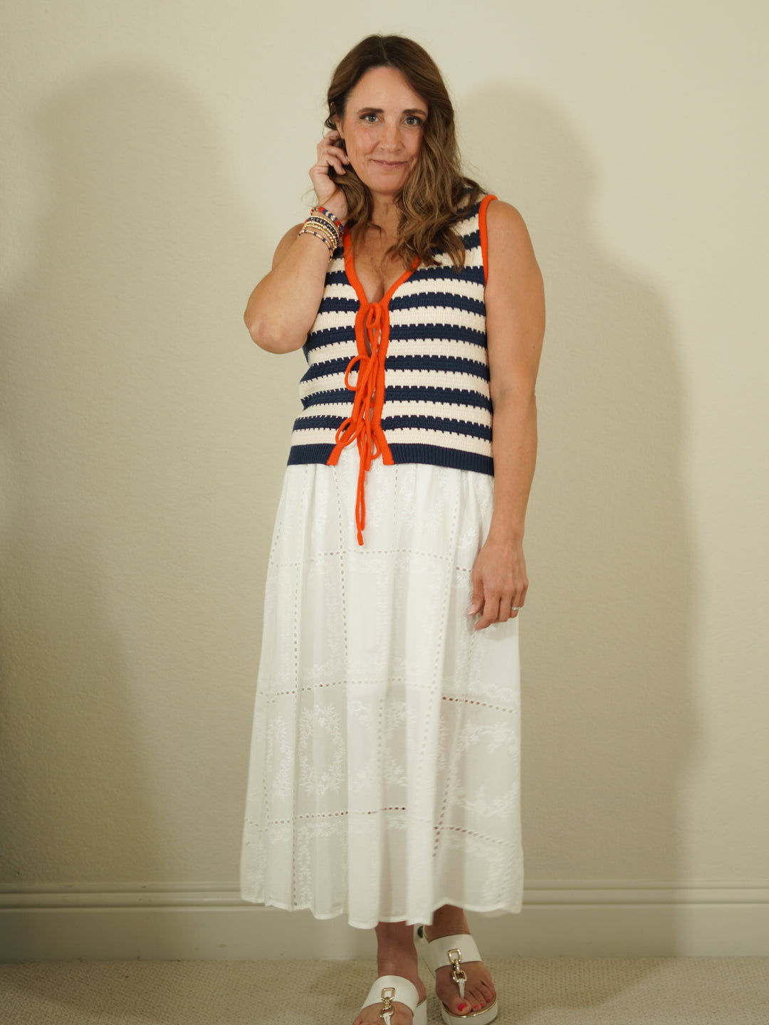Woman wearing a striped dress with orange accents against a plain background