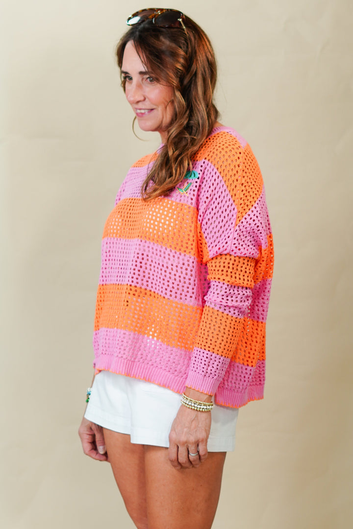Woman wearing a colorful striped sweater and white shorts against a beige background