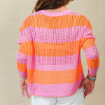 Person wearing a colorful striped sweater and white shorts against a plain background