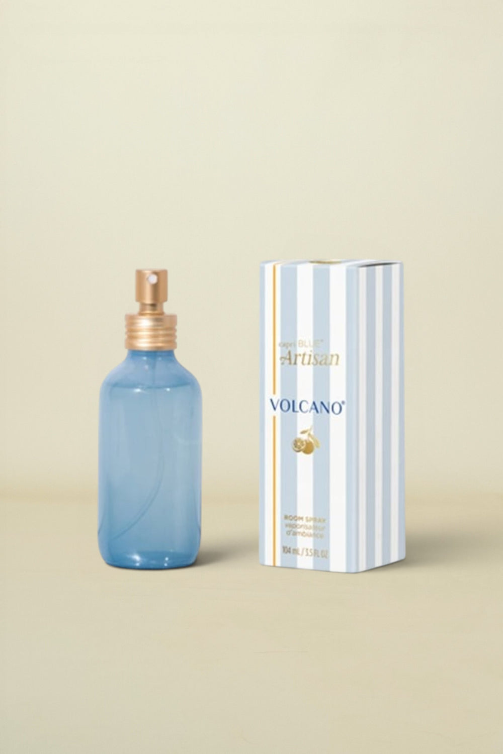 Blue spray bottle with gold cap and striped box labeled 'Artisan Volcano' on a white background