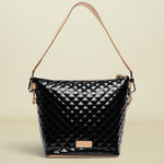 Black quilted handbag with tan handle and strap on a white background