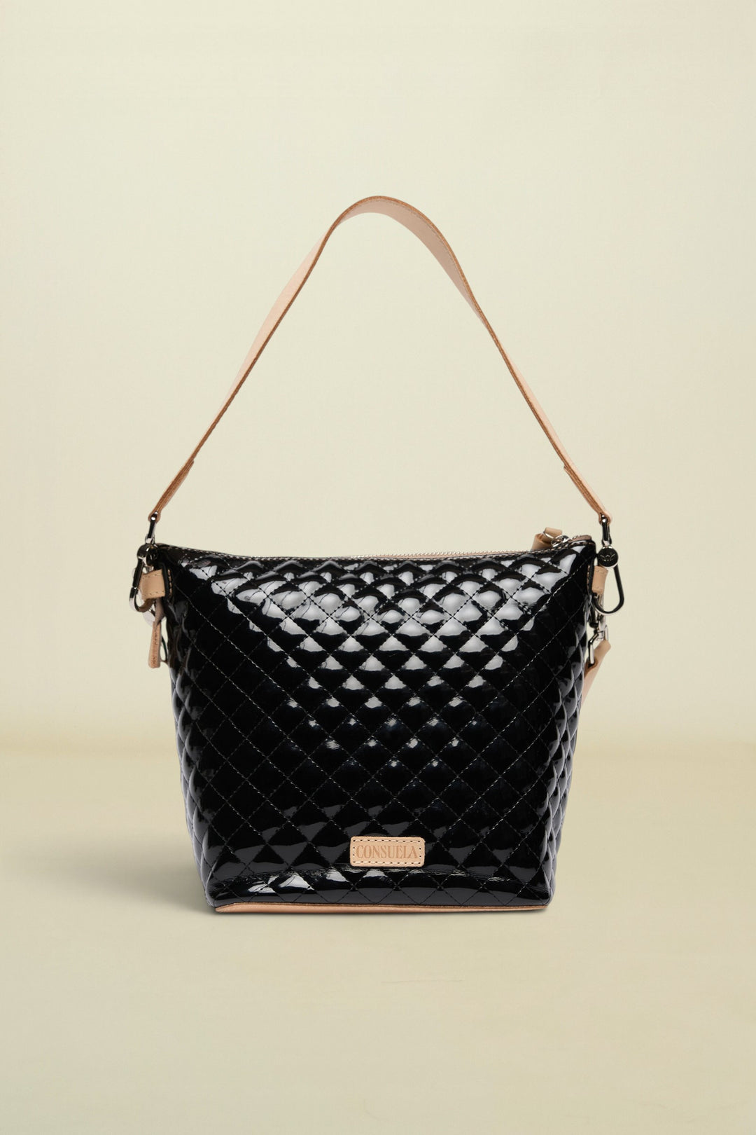 Black quilted handbag with tan handle and strap on a white background