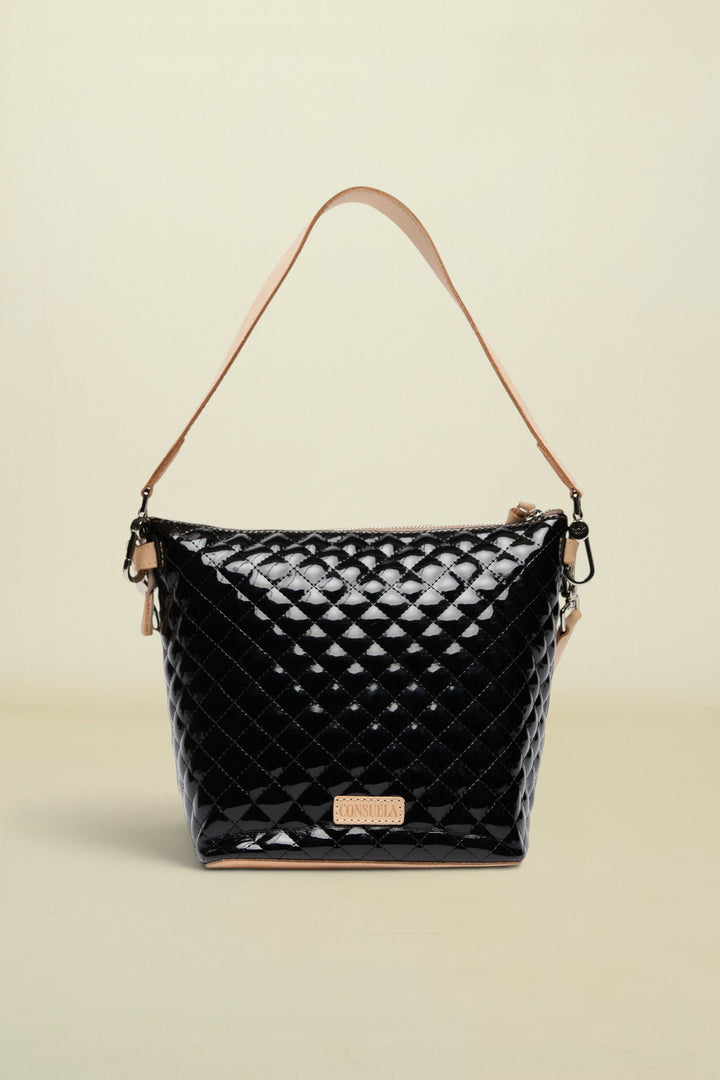Black quilted handbag with tan handle and strap on a white background
