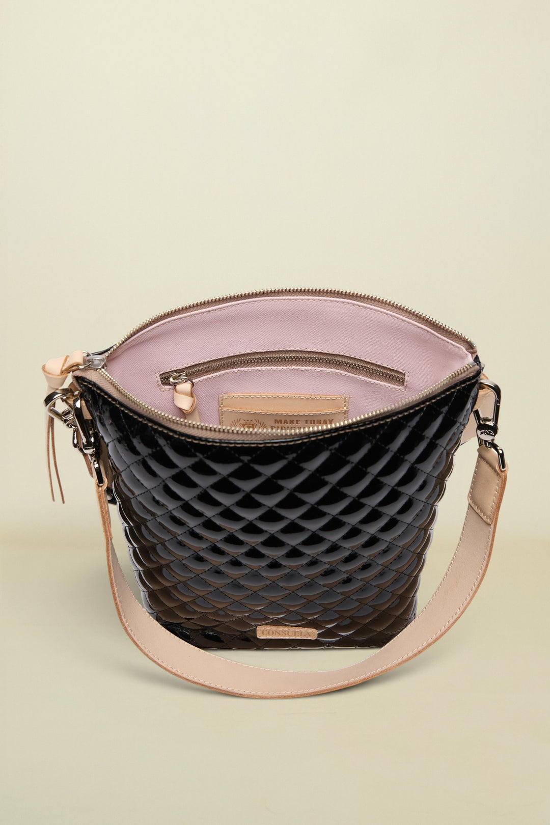 Black quilted handbag with beige interior and strap on a white background
