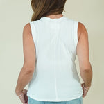 A woman shown from the back wearing a sleeveless white top and wide-leg light blue jeans, standing against a plain light beige studio background.