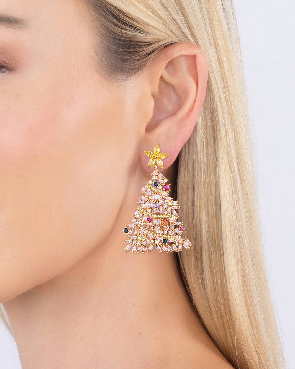 Close-up of a person wearing a colorful earring with a star design on a plain background