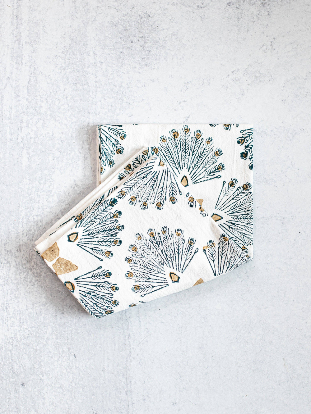 Two folded fabric napkins with floral pattern on a light gray surface