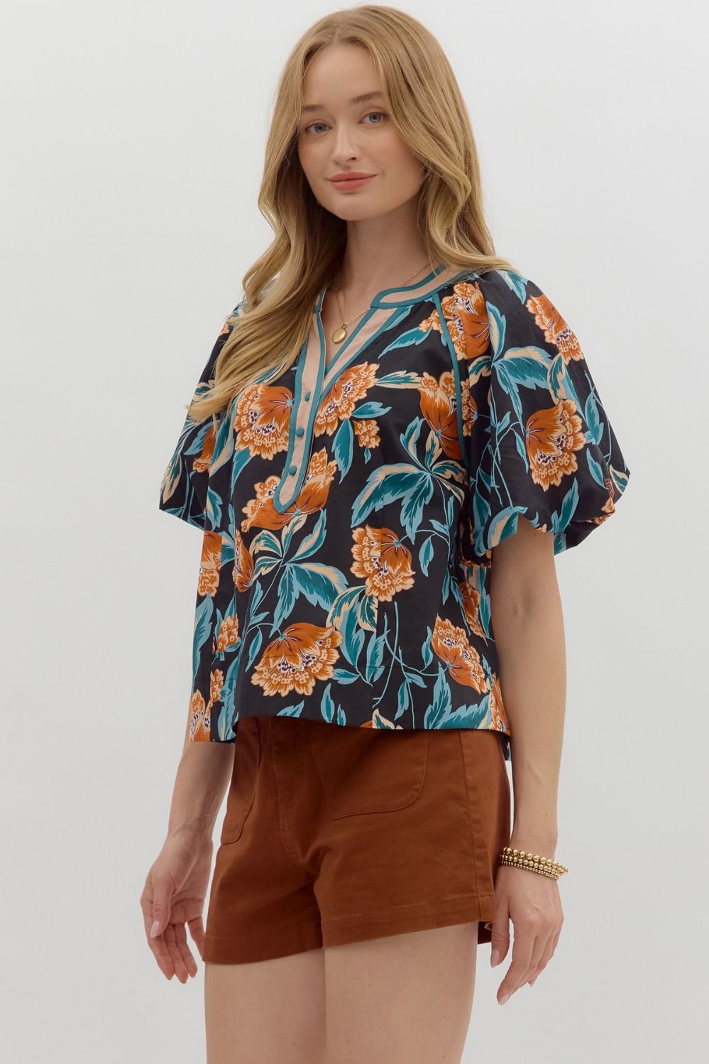 Woman wearing a floral blouse and brown shorts on a white background