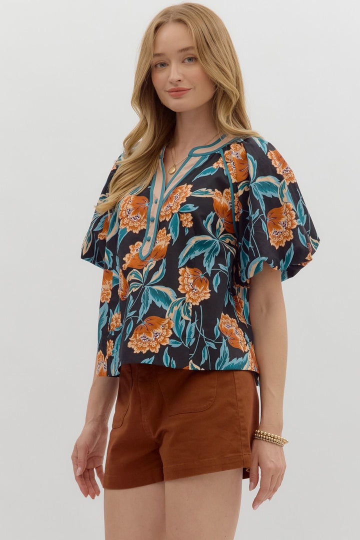 Woman wearing a floral blouse and brown shorts on a white background
