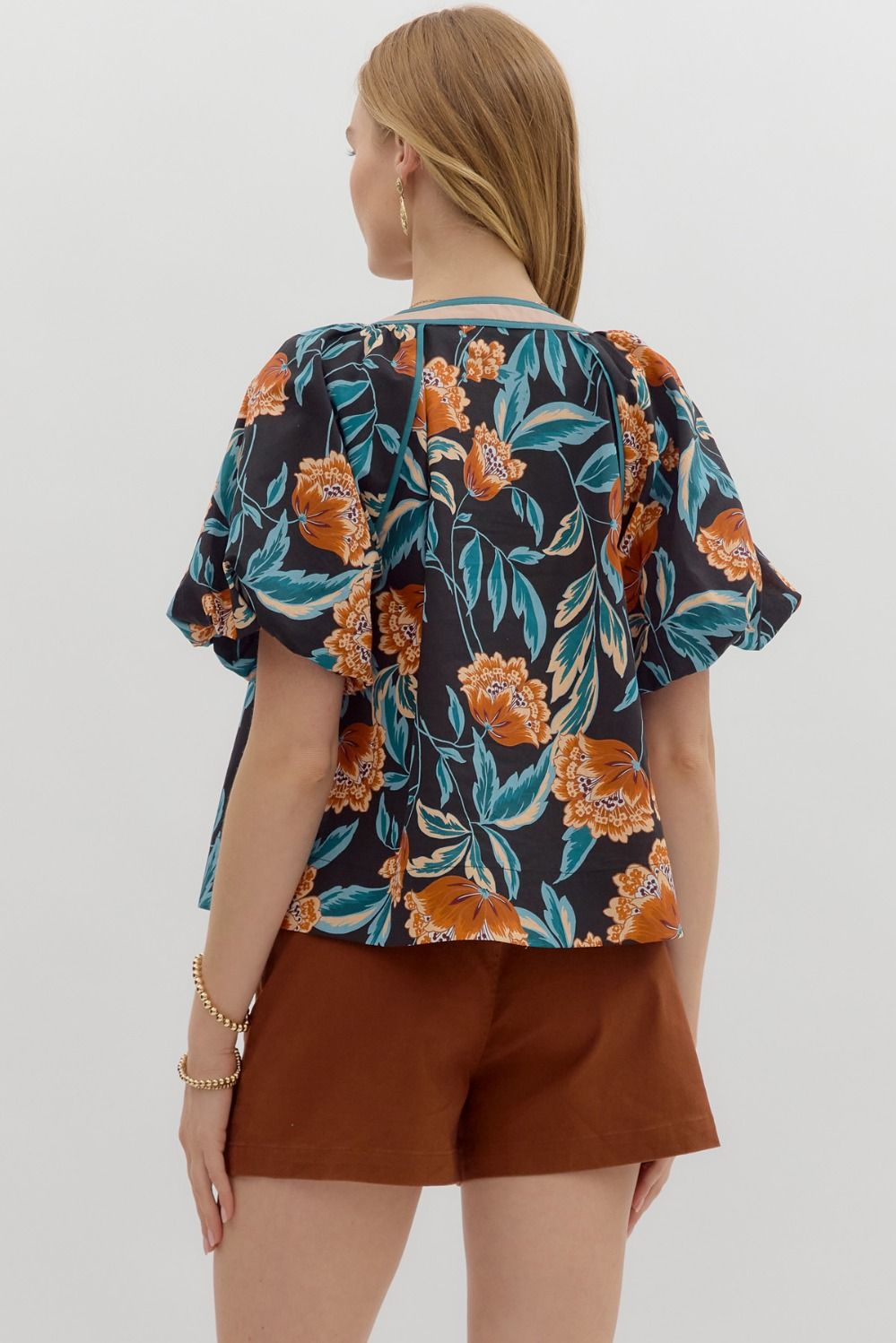 Woman wearing a floral blouse and brown shorts on a white background
