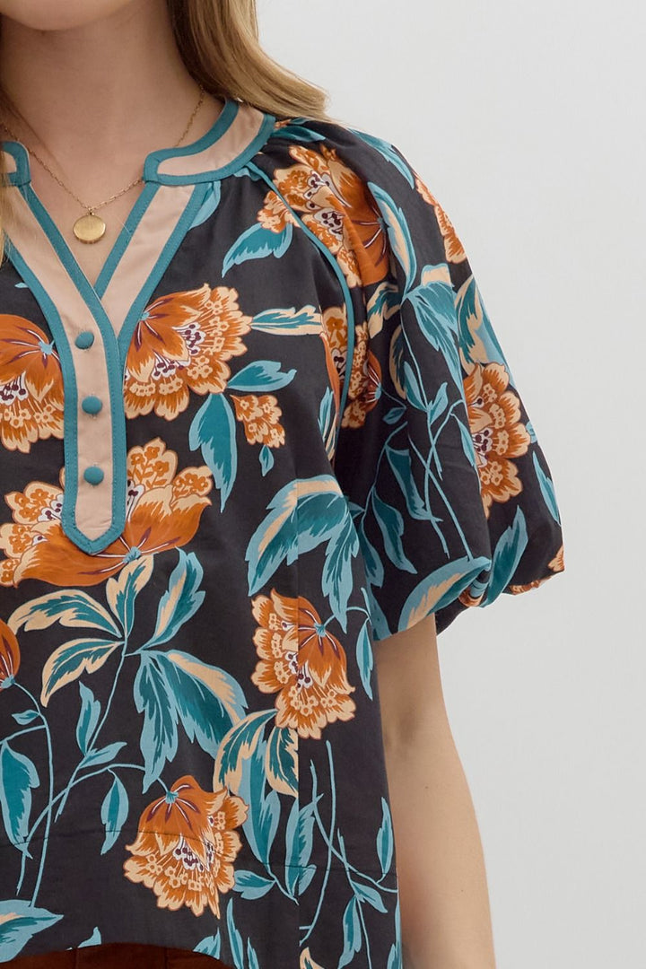 Floral patterned dress with orange and teal colors on a plain background