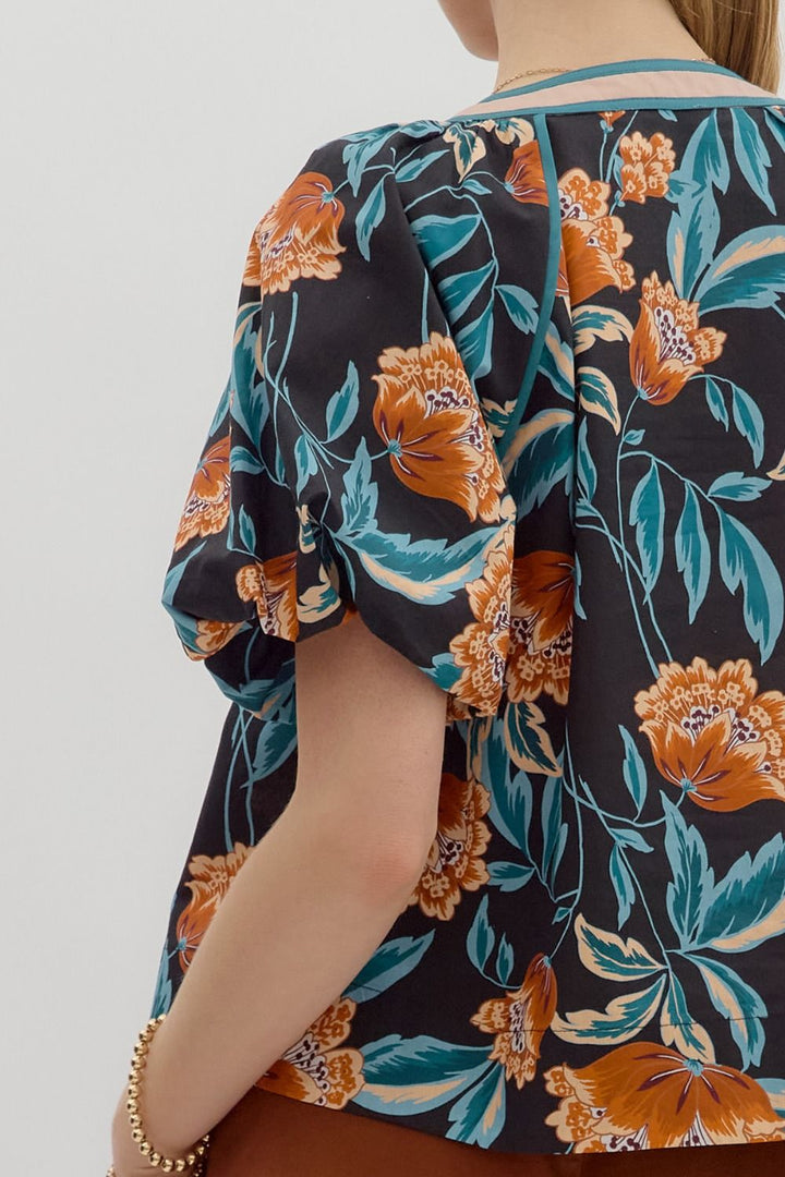 Floral patterned shirt with orange and green colors on a plain background