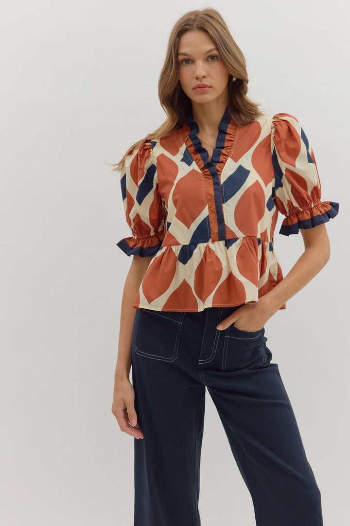 Woman wearing a patterned blouse with puff sleeves against a plain background