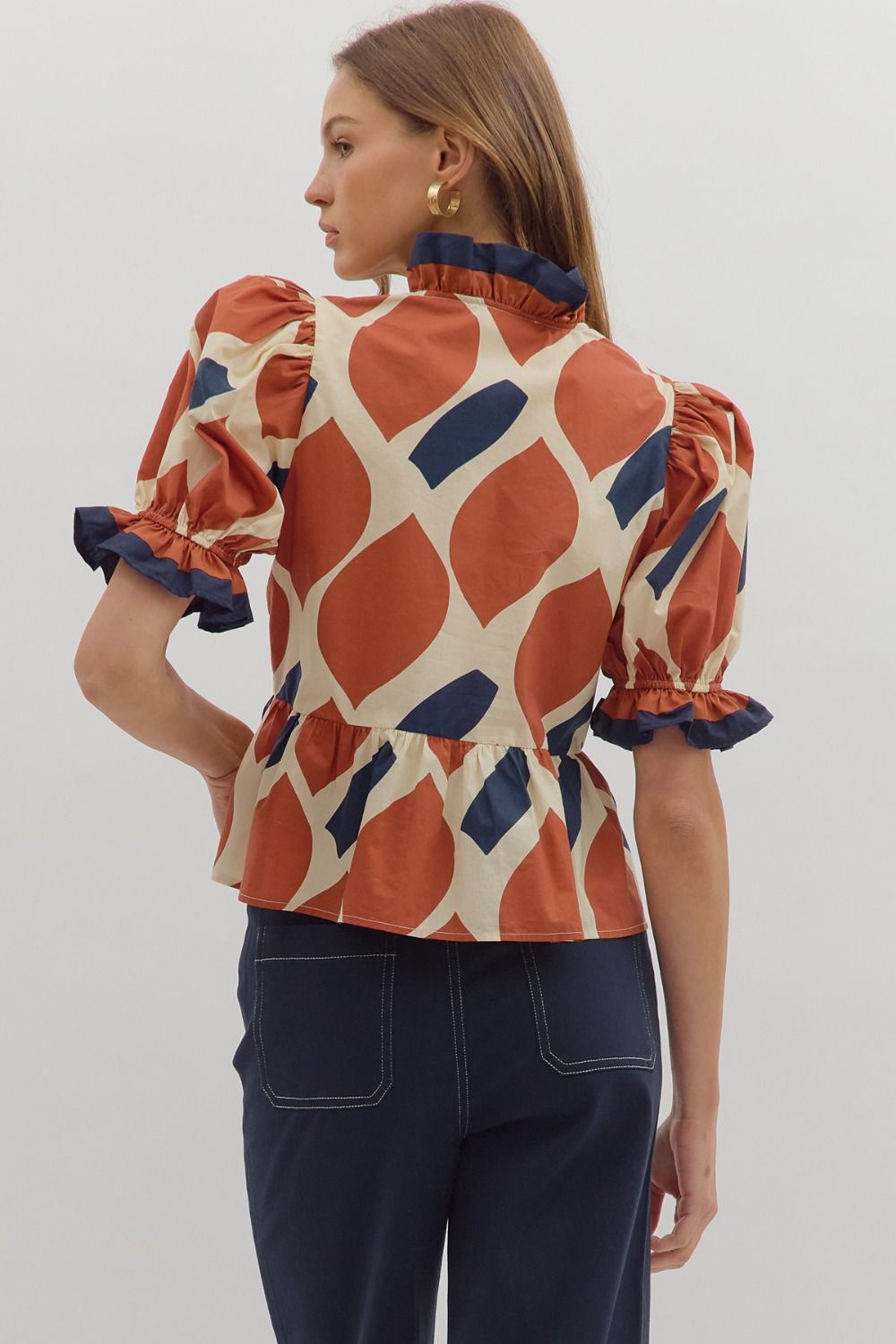 Woman wearing a patterned blouse with puff sleeves on a plain background