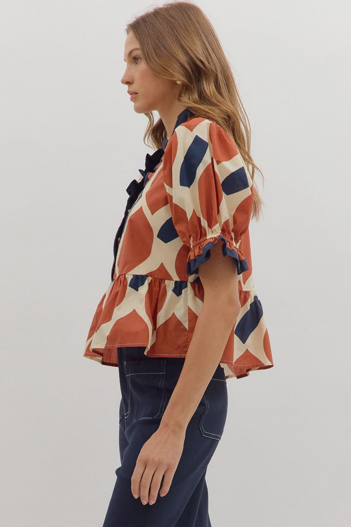 Woman wearing a patterned blouse with ruffled sleeves on a plain background