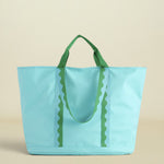 Light blue tote bag with green handles on a beige background