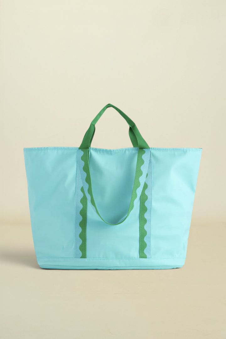 Light blue tote bag with green handles on a beige background