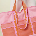 Person holding a pink and orange tote bag against a white background
