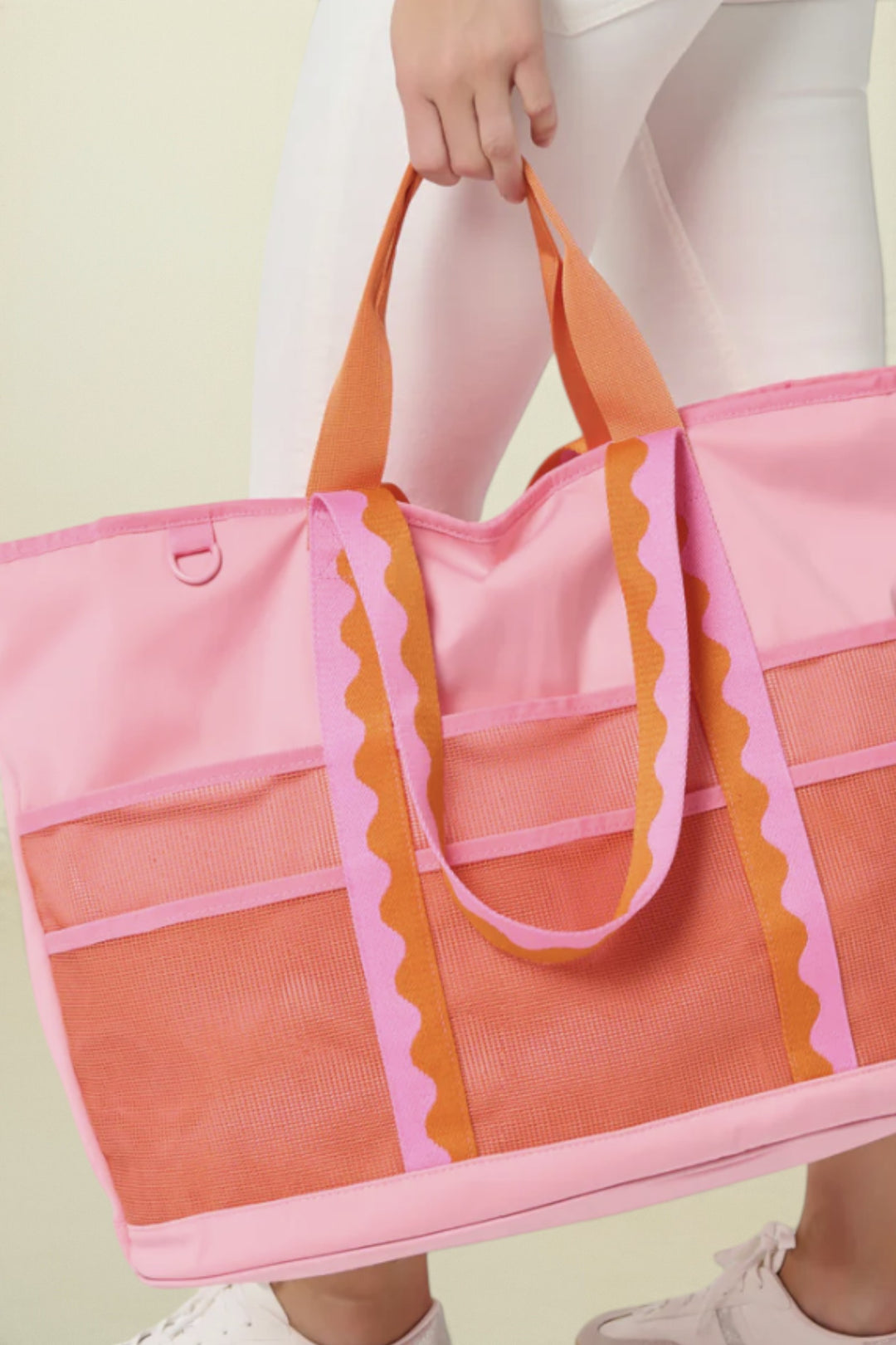 Person holding a pink and orange tote bag against a white background